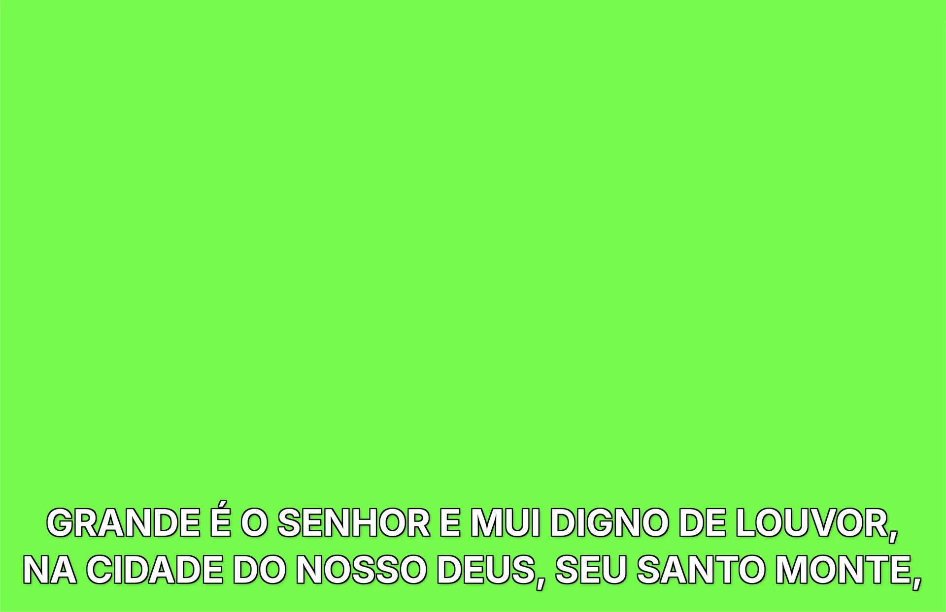 Telão em tela cheia no modo Legenda: duas linhas de letra branca com contorno preto sobre fundo verde.